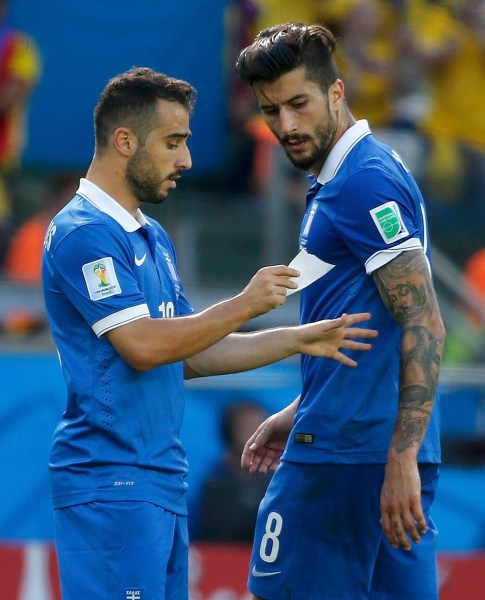 Greece's Fetfatzidis holds a piece of paper as his teammate Kone watches during their 2014 World Cup Group C soccer match against Colombia at the Mineirao stadium in Belo Horizonte