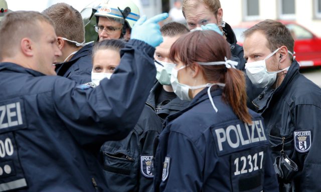 Police officers  wearing protective masks stand outside the job centre in the Berlin district of Pankow