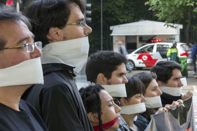 Integrantes de la organización no gubernamental Río de Paz permanecen con pañuelos que tapan sus bocas hoy, jueves 20 de agosto de 2015, en la avenida paulista, en Sao Paulo (Brasil), durante un acto de solidaridad con los familiares de las víctimas de la matanza ocurrida el pasado viernes en Osasco-Barueri, en la zona metropolitana de Sao Paulo, que interrumpió la vida de 18 brasileños habitantes de la periferia. EFE/SEBASTIÃO MOREIRA