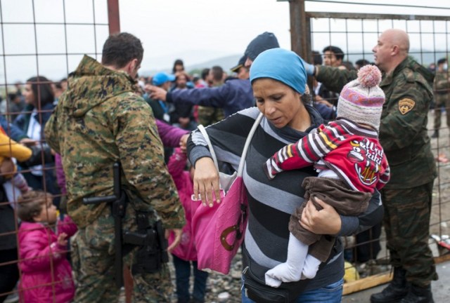 Policías macedonios controlar a una multitud de los migrantes y refugiados, mientras se preparan para entrar en un campamento después de cruzar la frontera con Grecia en Macedonia, cerca de Gevgelija el 8 de octubre de 2015. Macedonia es un país de tránsito clave en la ruta de migración de los Balcanes en la UE, con miles de solicitantes de asilo y migrantes - muchos de ellos procedentes de Siria, Afganistán, Irak y Somalia - que entran en el país todos los días. AFP PHOTO / ROBERT Atanasovski