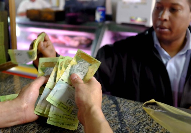 Un cajero cuenta bolívar en una carnicería en un mercado público en Caracas, Venezuela el 22 de enero de 2016. La oposición de Venezuela rechazó el viernes aprobar el decreto de "emergencia económica" del presidente Nicolás Maduro en el Congreso, diciendo que no ofreció soluciones para la nación OPEP cada vez más desastrosa recesión. Subrayando la grave situación en Venezuela, donde una caída en los precios del petróleo ha agravado las políticas disfuncionales, el viernes el Fondo Monetario Internacional pronosticó una caída del 8 por ciento en el producto interno bruto y una inflación del 720 por ciento este año. REUTERS / Marco Bello