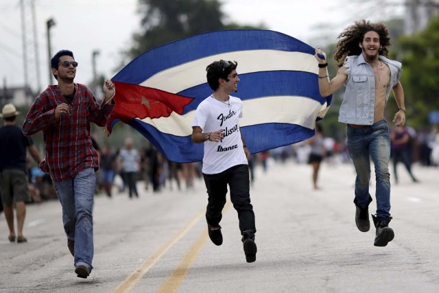 Fans run with a Cuban flag outside Ciudad Deportiva de la Habana sports complex where the Rolling Stones' free outdoor concert will take place today in Havana, March 25, 2016. REUTERS/Ueslei Marcelino