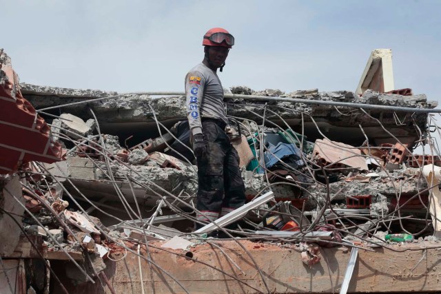 A rescuer searches for victims in Jama, in the Ecuadorean coastal province of Manabi, on April 18, 2016 two days after a 7.8-magnitude quake hit the country, on April 18, 2016. Rescuers and desperate families clawed through the rubble Monday to pull out survivors of an earthquake that killed 350 people and destroyed towns in a tourist area of Ecuador. / AFP PHOTO / Juan Cevallos