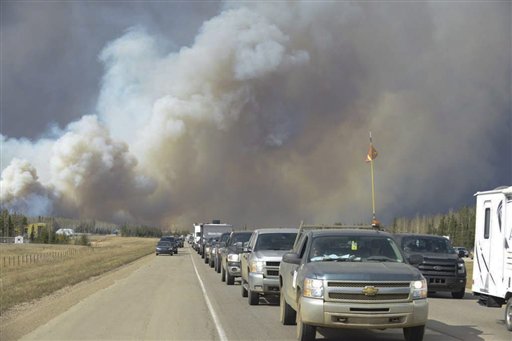 Humo cubre el aire y árboles están en llamas en Fort McMurray, Alberta, el martes 3 de mayo de 2016. La población completa de la ciudad canadiense en la región de arenas bituminosas Fort McMurray, Alberta, ha sido obligada a evacuar cuando las llamas de un incendio comenzaron a avanzar hacia ella. (Kitty Cochrane/The Canadian Press vía AP) CRÉDITO OBLIGATORIO
