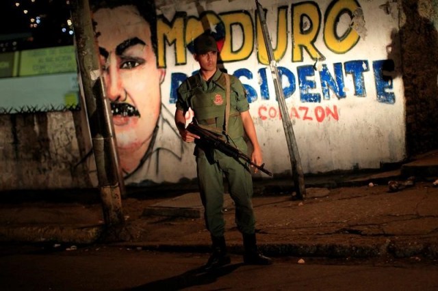 Imagen de archivo de un soldado venezolano parado frente a un mural del presidente Nicolás Maduro, durante un operativo de seguridad en Caracas, Venezuela,23 de mayo 2013. La Fiscalía de Venezuela informó el domingo que imputará a 11 funcionarios militares por el asesinato de 12 personas en un operativo de seguridad, cuyos cuerpos fueron localizados en una zona montañosa del central estado Miranda, más de un mes después de que se les reportó como desaparecidos. REUTERS/Jorge Silva