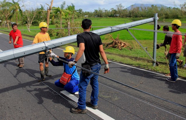 Workers check downed electric posts on the national road after typhoon Nock-Ten made landfall in Nabua, Camarines Sur on December 26, 2016. Typhoon Nock-Ten, which made landfall on the eastern island province of Catanduanes on December 25, is forecast to move westward towards the country's heartland, packing winds of 215 kilometres (134 miles) per hour. / AFP PHOTO / Charism SAYAT