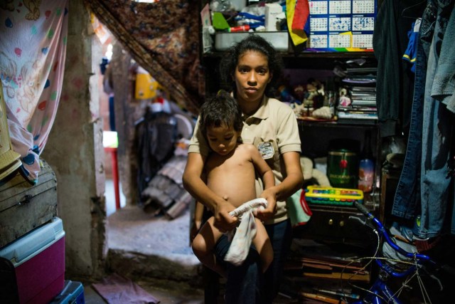 Venezuelan Rebeca Leon, who scavanges for food in the streets of Caracas, poses with her two-year-old son at her house in Petare shantytown, on February 22, 2017. Venezuelan President Nicolas Maduro is resisting opposition efforts to hold a vote on removing him from office. The opposition blames him for an economic crisis that has caused food shortages. / AFP PHOTO / Federico PARRA