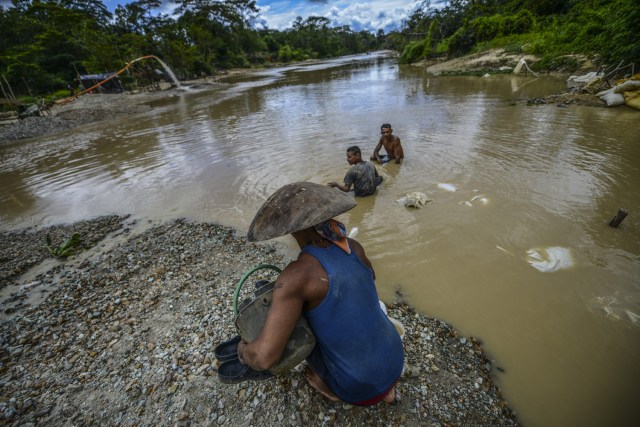 Men work at Nacupay gold mine on the bank of a river in El Callao, Bolivar state, southeastern Venezuela on February 24, 2017. Although life in the mines of eastern Venezuela is hard and dangerous, tens of thousands from all over the country head for the mines daily in overcrowded trucks, pushed by the rise in gold prices and by the severe economic crisis affecting the country, aggravated recently by the drop in oil prices. / AFP PHOTO / JUAN BARRETO