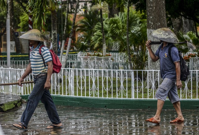 Gold miners with pans on their heads walk along one of the main streets in El Callao, Bolivar state, southeastern Venezuela on February 25, 2017. Although life in the mines of eastern Venezuela is hard and dangerous, tens of thousands from all over the country head for the mines daily in overcrowded trucks, pushed by the rise in gold prices and by the severe economic crisis affecting the country, aggravated recently by the drop in oil prices. / AFP PHOTO / JUAN BARRETO