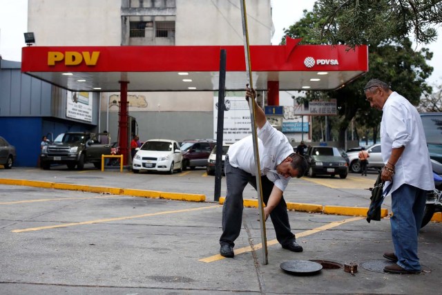 Gas station workers inspect the level of the gasoline tanks of a gas station of the state oil company PDVSA in Caracas, Venezuela March 22, 2017. REUTERS/Carlos Garcia Rawlins