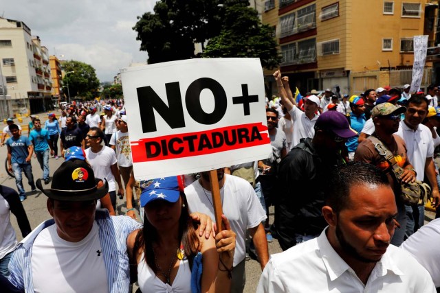 Demonstrators take part in a rally to honor the victims of violence during the protests and against Venezuela's President Nicolas Maduro's government in Caracas, Venezuela, April 22, 2017. Placard reads  "No more dictatorship" REUTERS/Carlos Garcia Rawlins