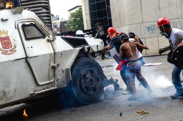 A Venezuelan National Guard riot control vehicle runs over an opposition demonstrator during a protest against Venezuelan President Nicolas Maduro, in Caracas on May 3, 2017. Venezuelan police fired tear gas and hooded protesters hurled Molotov cocktails as thousands rallied Wednesday in anger at President Nicolas Maduro's plan to rewrite the constitution. At least one protester caught fire and two opposition lawmakers were among various people injured, AFP reporters at the scene said. / AFP PHOTO / FEDERICO PARRA