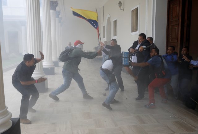 A goverment supporter holds a National flag while clashing with people outside Venezuela's opposition-controlled National Assembly, in Caracas, Venezuela July 5, 2017. REUTERS/Andres Martinez Casares