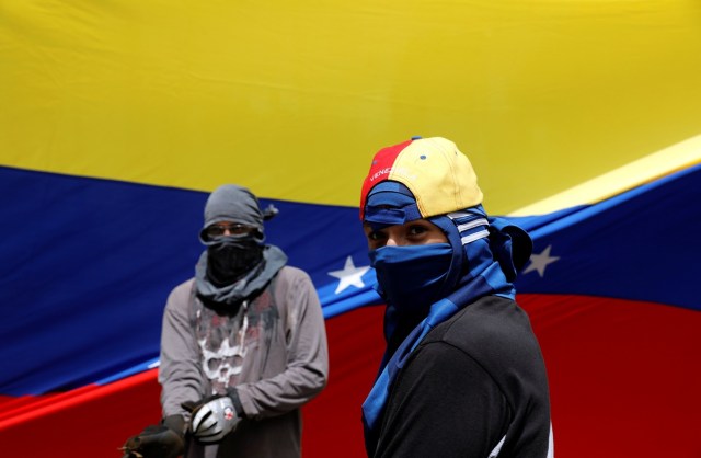 Masked demonstrators stand in front of a Venezuelan national flag during a rally against Venezuelan President Nicolas Maduro's government in Caracas, Venezuela July 10, 2017. REUTERS/Andres Martinez Casares
