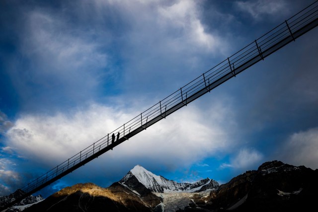 A couple walks on the "Europabruecke",  supposed to be the world's longest pedestrian suspension bridge with a length of 494m, prior to the official inauguration of the construction in Randa, Switzerland, on Saturday, July 29, 2017. The bridge is situated on the Europaweg that connects the villages of Zermatt and Graechen. (Valentin Flauraud/Keystone via AP)