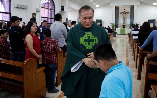 Roman Catholic priest Monsignor James Benavente gives a blessing to a boy after a Sunday mass at Sta Barbara Church on the island of Guam, a U.S. Pacific Territory, August 13, 2017.  REUTERS/Erik De Castro