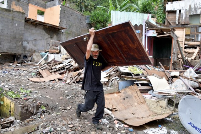 A man carries a door amid the rubble of his destroyed house after tropical storm Nate struck the Los Anonos neighbourhood in San Jose, on October 6, 2017.  In Costa Rica, where a national emergency was declared, eight people died, including a three-year-old girl, after they were hit by falling trees and mudslides. An alert was issued for people to be wary of crocodiles that might be roaming after rivers and estuaries flooded. / AFP PHOTO / EzequielBECERRA