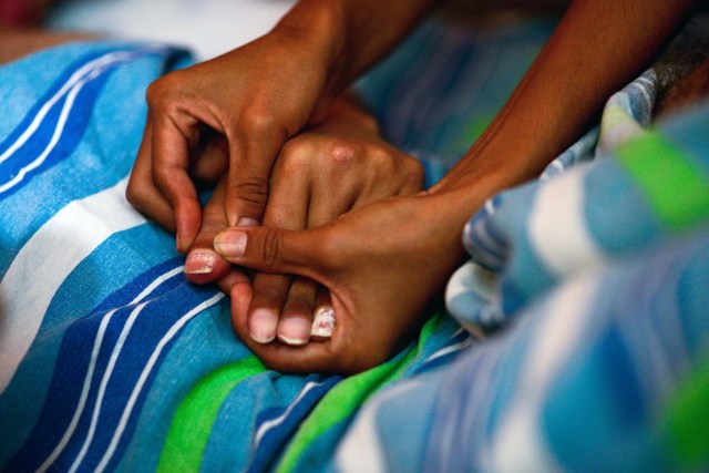 Ana Barrios wife of Marco Guillen, a 45-year-old quadriplegic, shows her husband's hands during a interview with AFP at their house in Barquisimeto, Lara state, Venezuela on October 23, 2017. Marco Guillen became quadriplegic in an accident twelve years ago, amid Venezuela's deep economical crisis he desperately asks President Maduro's government to help him to live with dignity, meeting his medical necessities otherwise he pleads for euthanasia. / AFP PHOTO / FEDERICO PARRA / TO GO WITH AFP STORY by MARGIONI BERMUDEZ