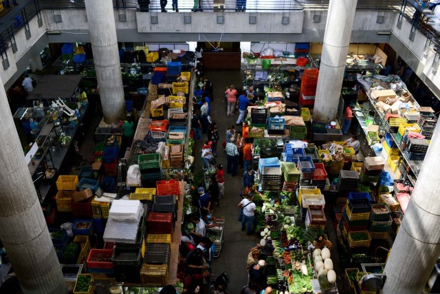 People shop at the municipal market of Chacao in Caracas on November 2, 2017. This week, Venezuelan President Nicolas Maduro introduced a new bank note of 100,000 Bolivars - five times the current largest denomination - and announced a 30 percent minimum wage hike. / AFP PHOTO / FEDERICO PARRA