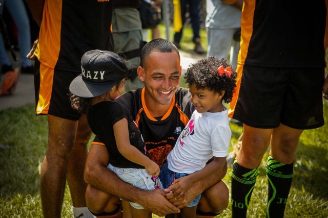 ACOMPAÑA CRÓNICA: RUGBY VENEZUELA - CAR101. MARACAY (VENEZUELA), 02/12/2017.- Fotografía del viernes 1 de diciembre de 2017, que muestra a un preso mientras comparte con dos niñas durante un torneo de Rugby entre equipos conformados por internos de ocho prisiones venezolanas en la Hacienda Santa Teresa, sede de la compañía manufacturera de Ron del mismo nombre en Maracay (Venezuela). EFE/Cristian Hernández