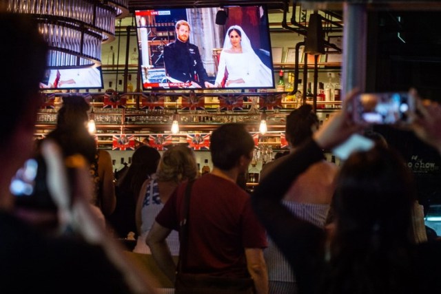 People watch the live broadcasting showing the wedding ceremony of Britain's Prince Harry, Duke of Sussex and his wife Meghan, Duchess of Sussex in Windsor, in Hong Kong on May 19, 2018. / AFP PHOTO / Philip FONG