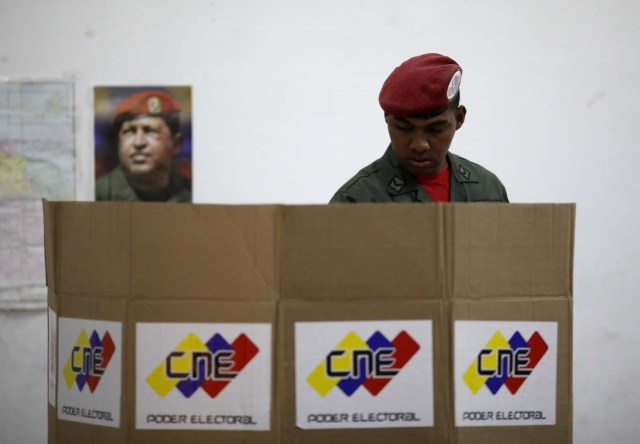 With an image of the late Venezuelan President Hugo Chavez behind him a Venezuelan soldier casts his vote at a polling station during the presidential election in Caracas, Venezuela, May 20, 2018. REUTERS/Carlos Garcia Rawlins