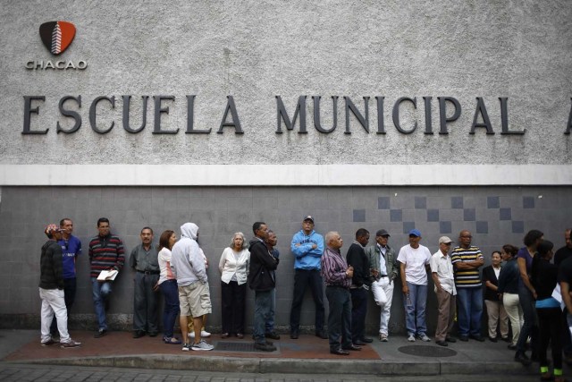 Venezuelan citizens wait in line to vote at a polling station situated inside a school during the presidential election in Caracas, Venezuela, May 20, 2018. REUTERS/Adriana Loureiro