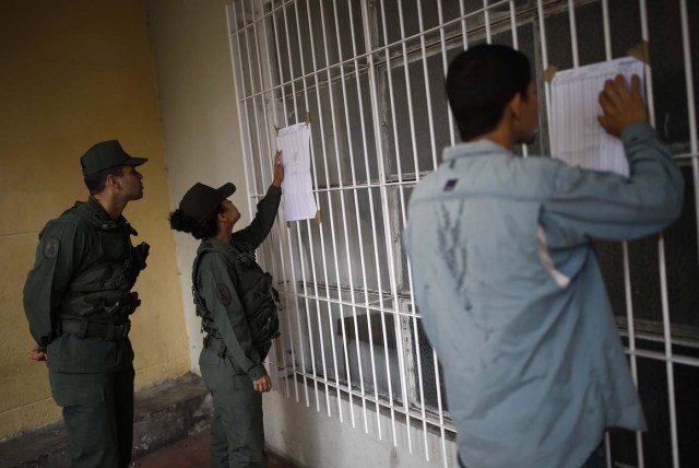 Venezuelan soldiers and a civilian check electoral lists at a polling station during the presidential election in Caracas, Venezuela, May 20, 2018. REUTERS/Carlos Garcia Rawlins