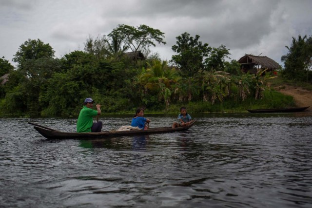 Fotografía fechada el 10 de mayo de 2018 que muestra a una familia Warao a bordo de una curiara (pequeña embarcación) mientras navegan por el río Morichal, en Maturín (Venezuela). Unos 120 indígenas distribuidos en cerca de 30 palafitos de precaria elaboración conforman la comunidad de Morichal Largo, un asentamiento de la etnia Warao ubicado en el sur de Venezuela, que resiste debajo de un puente la miseria e insalubridad propia de la crisis nacional. EFE/Cristian Hernández