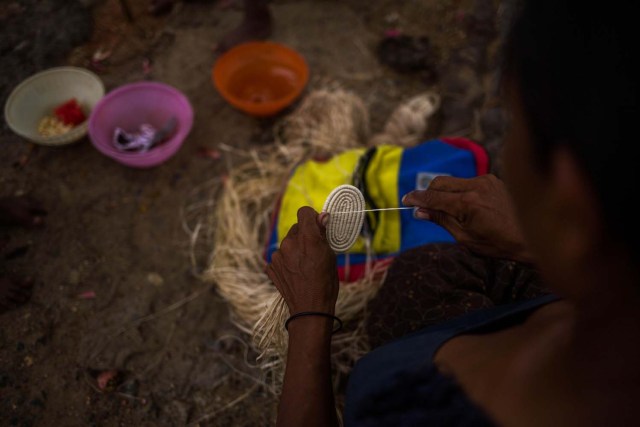 Fotografía fechada el 10 de mayo de 2018 que muestra a una mujer de la etnia Warao mientras elabora un tejido con fibra de palma de Morichal, en Maturín (Venezuela). Unos 120 indígenas distribuidos en cerca de 30 palafitos de precaria elaboración conforman la comunidad de Morichal Largo, un asentamiento de la etnia Warao ubicado en el sur de Venezuela, que resiste debajo de un puente la miseria e insalubridad propia de la crisis nacional. EFE/Cristian Hernández