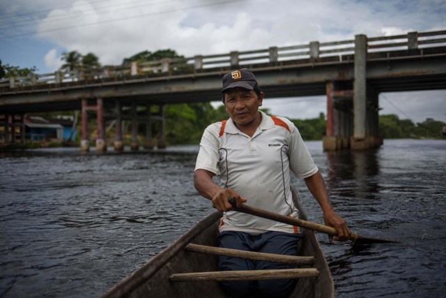 Fotografía fechada el 10 de mayo de 2018 que muestra a Hernán a bordo de una curiara (pequeña embarcación) mientras navega en el río Morichal, en Maturín (Venezuela). Unos 120 indígenas distribuidos en cerca de 30 palafitos de precaria elaboración conforman la comunidad de Morichal Largo, un asentamiento de la etnia Warao ubicado en el sur de Venezuela, que resiste debajo de un puente la miseria e insalubridad propia de la crisis nacional. EFE/Cristian Hernández